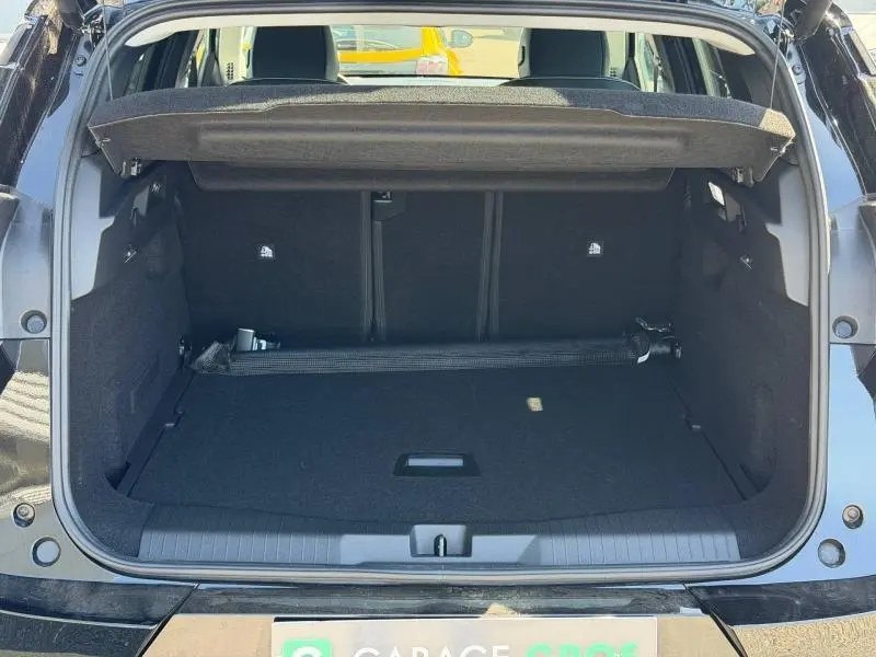 Coffre ouvert vu de l'arrière d'un Citroën C5 Aircross noir Perla Nera avec cache-bagages relevé et intérieur spacieux.