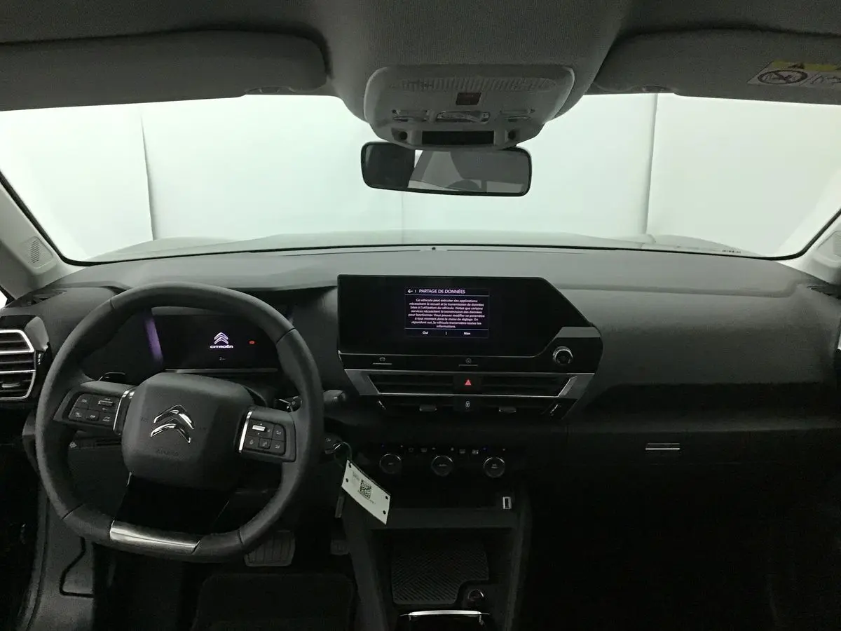 Intérieur noir du Citroën C4 2022 vu de face, tableau de bord moderne avec écran tactile central allumé.
