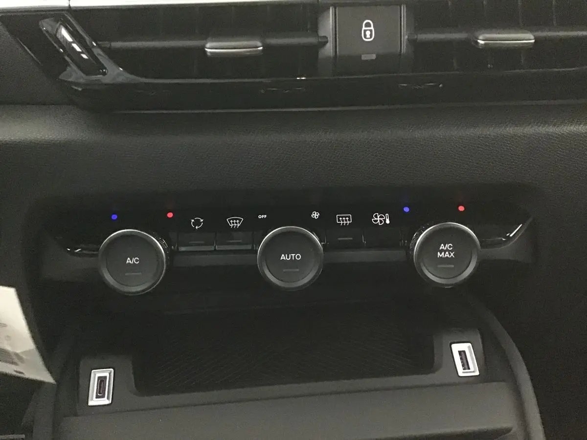 Vue rapprochée du tableau de bord noir de la Citroën C4 2022, mettant en valeur les commandes de climatisation et ports USB.