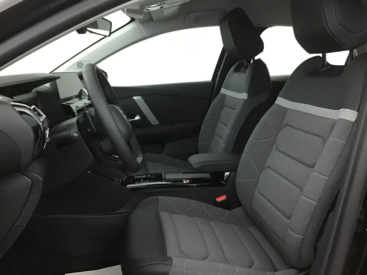 Vue intérieure côté conducteur de la Citroën C4 2022 avec sièges tissu gris et tableau de bord moderne noir.