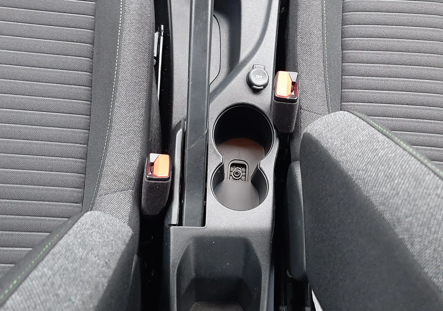 Vue plongeante sur la console centrale grise avec frein à main, porte-gobelets et sièges tissu gris du Peugeot 208 2024.