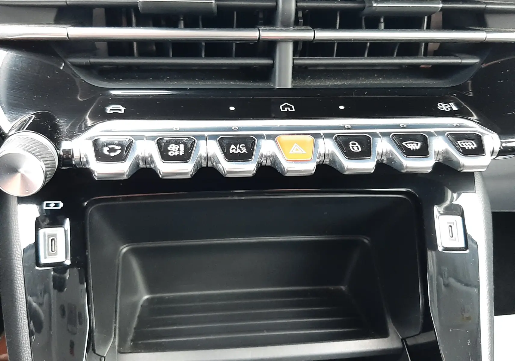 Vue rapprochée de la console centrale noire brillante de la Peugeot 208 2024 avec boutons de commande chromés et voyants lumineux.