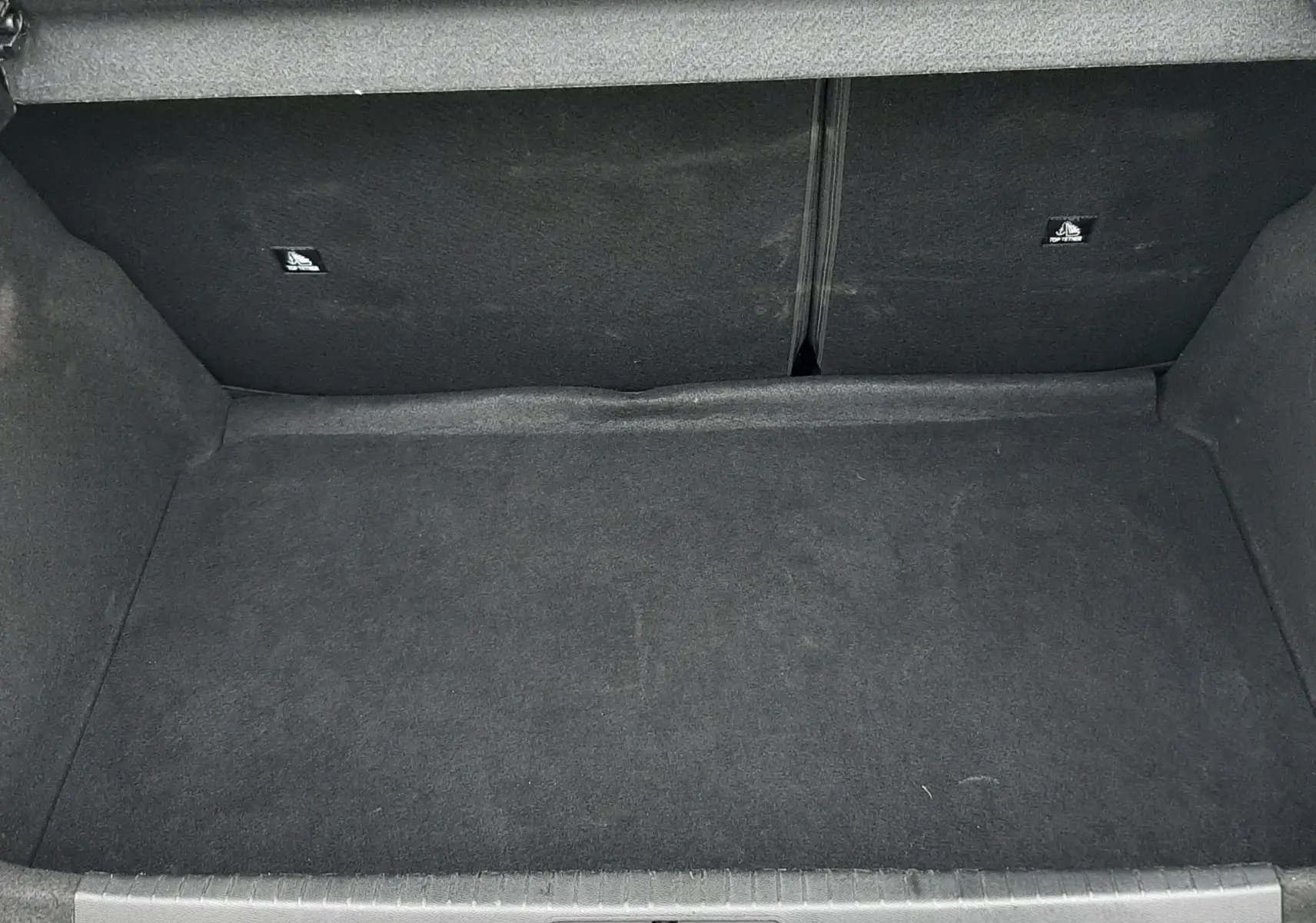 Coffre ouvert de la Peugeot 208 gris selenium 2024, vue plongeante sur l'espace de rangement vide et tapis noir.