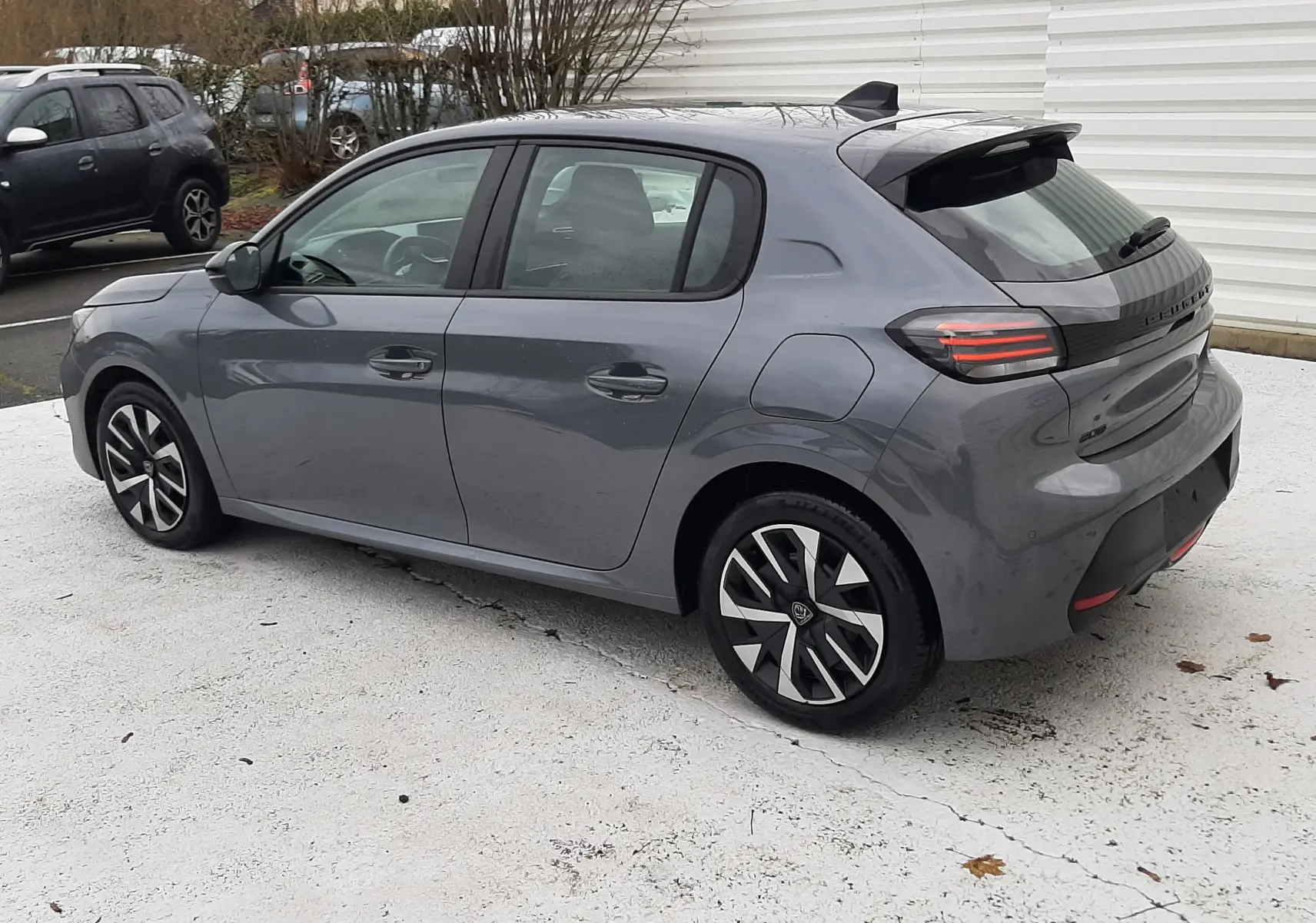 Peugeot 208 gris sélénium vue 3/4 arrière côté gauche, avec jantes alliage et toit avec antenne requin.
