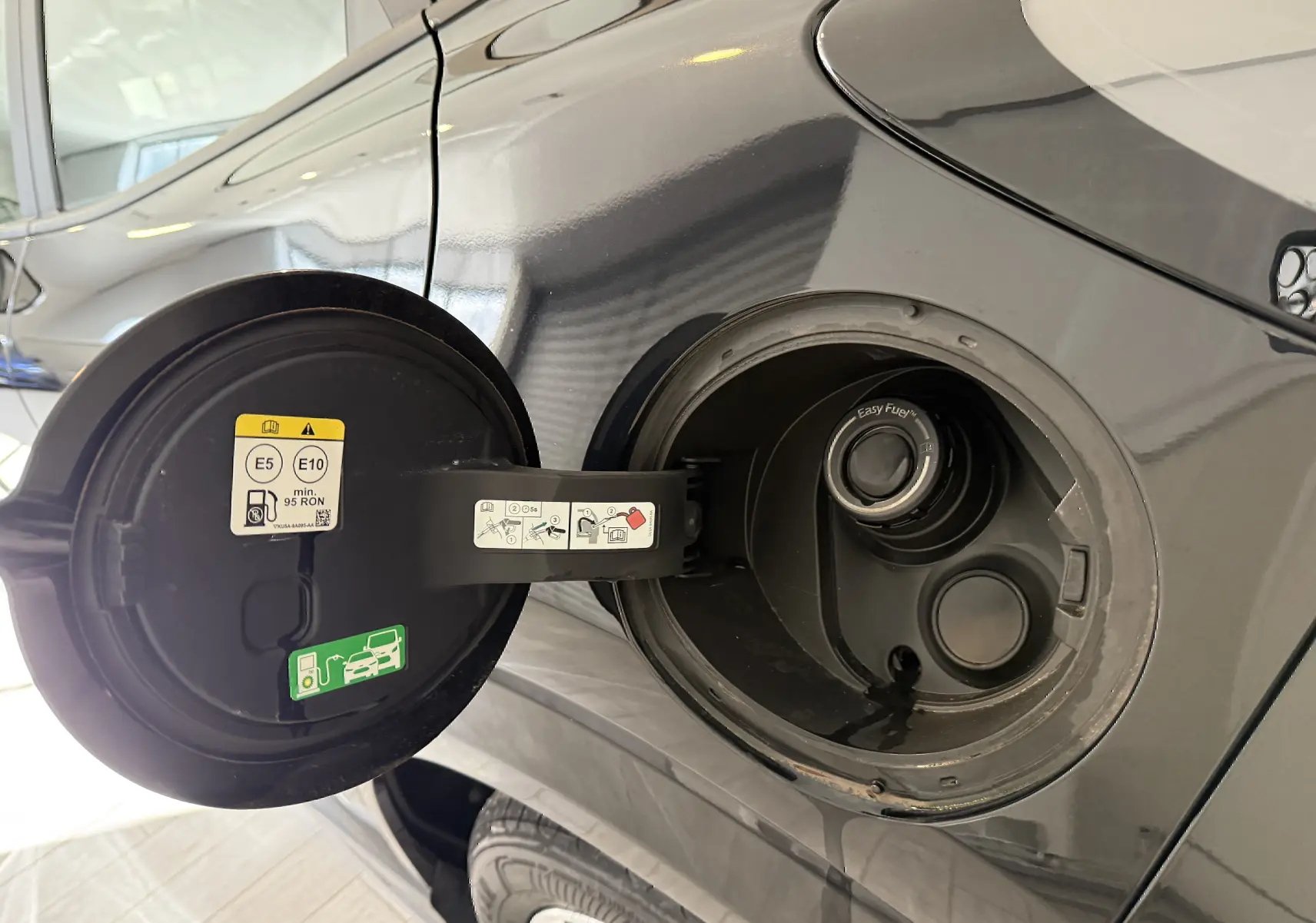 Détail de la trappe à carburant ouverte côté gauche d’un Ford Puma noir agate avec bouchon Easy Fuel visible.