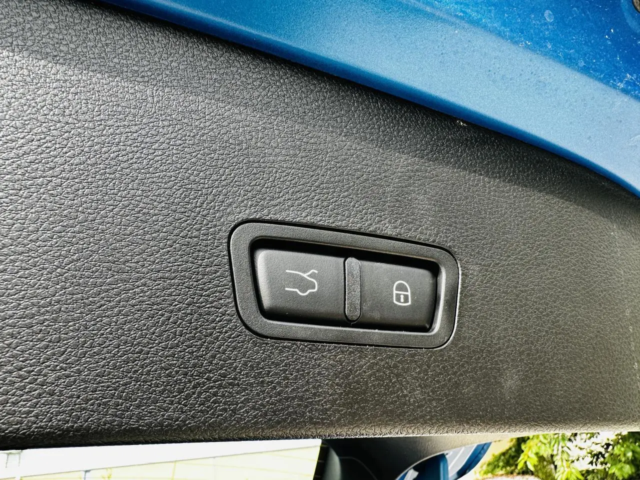 Gros plan sur les boutons de hayon électrique et verrouillage, sous l'ouverture arrière bleu métallisé d'une Alfa Romeo Tonale.