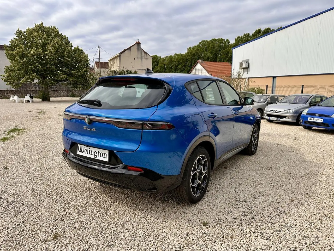Vue 3/4 arrière droite d'une Alfa Romeo Tonale bleu métallisé avec feux arrière LED et jantes distinctives.