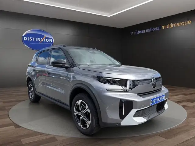 Citroën C3 Aircross Electric gris mercury avec toit noir, vue 3/4 avant en intérieur showroom, détails modernes et phares LED.