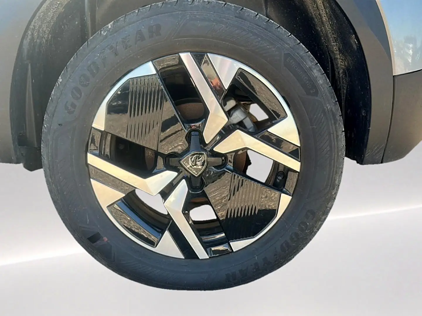 Gros plan sur la jante alu bicolore noire et argentée d’un Peugeot 2008 gris Artense, roue avant droite.