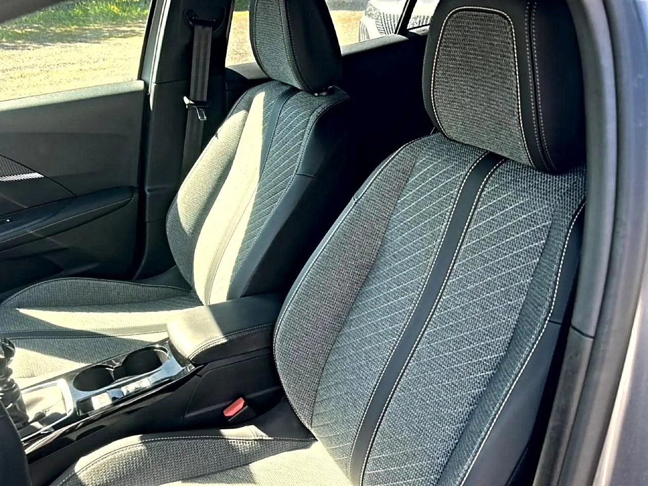 Vue intérieure rapprochée des sièges avant en tissu gris embossé du Peugeot 2008 1.2 100 allure 2025.