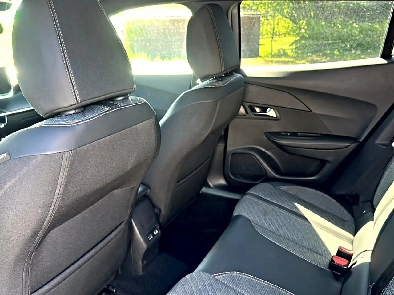 Vue intérieure arrière droite de la Peugeot 2008 1.2 100 Allure avec sièges tissu noir et gris embossé.