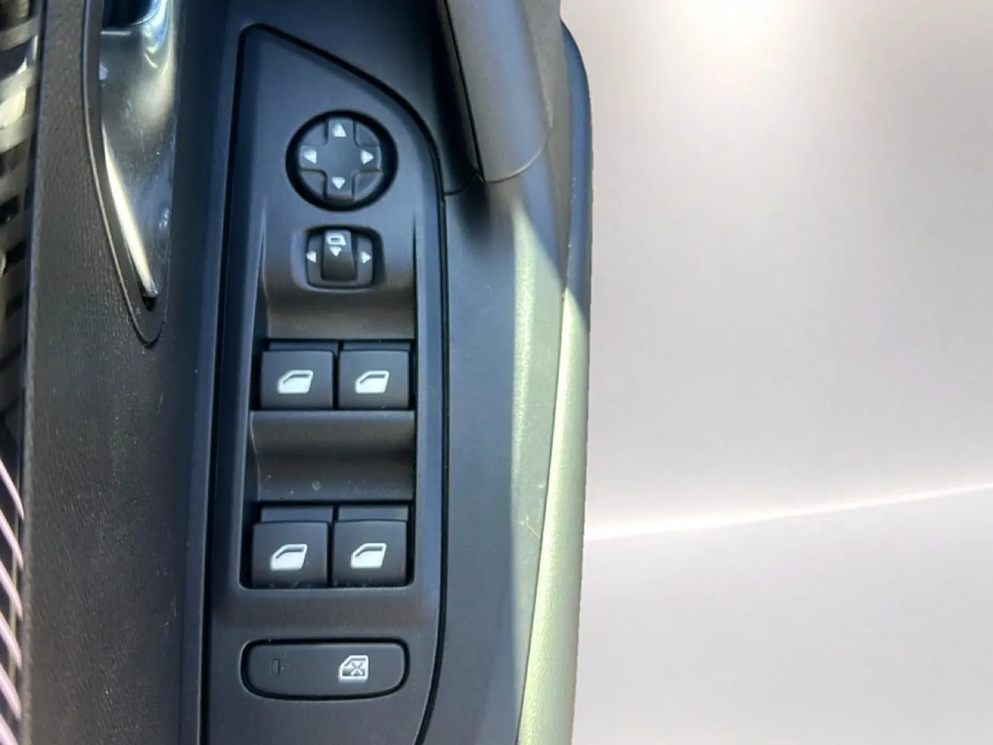 Gros plan sur la commande des vitres électriques côté conducteur d’un Peugeot 2008 gris Artense.