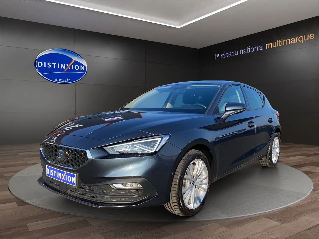 SEAT Leon gris magnetic vue 3/4 avant droit, avec jantes alu 17 pouces et phares full LED allumés.