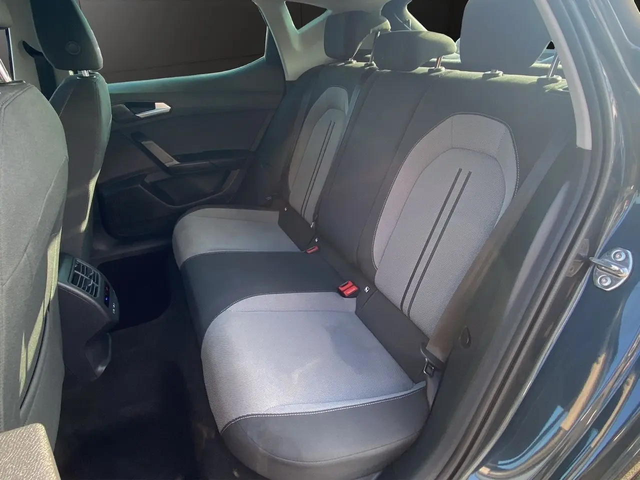 Vue intérieure côté droit sur les sièges arrière en tissu noir et gris d'une SEAT LEON IV 2024 avec portière ouverte.