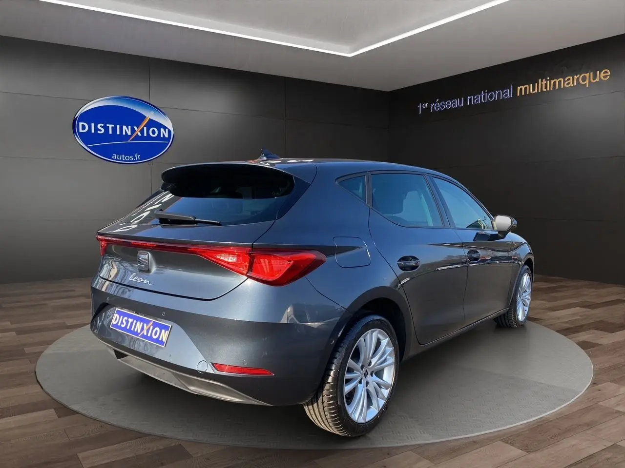 SEAT Leon gris magnetic vue 3/4 arrière droit, jantes alu 17 pouces et feux arrière LED dans showroom