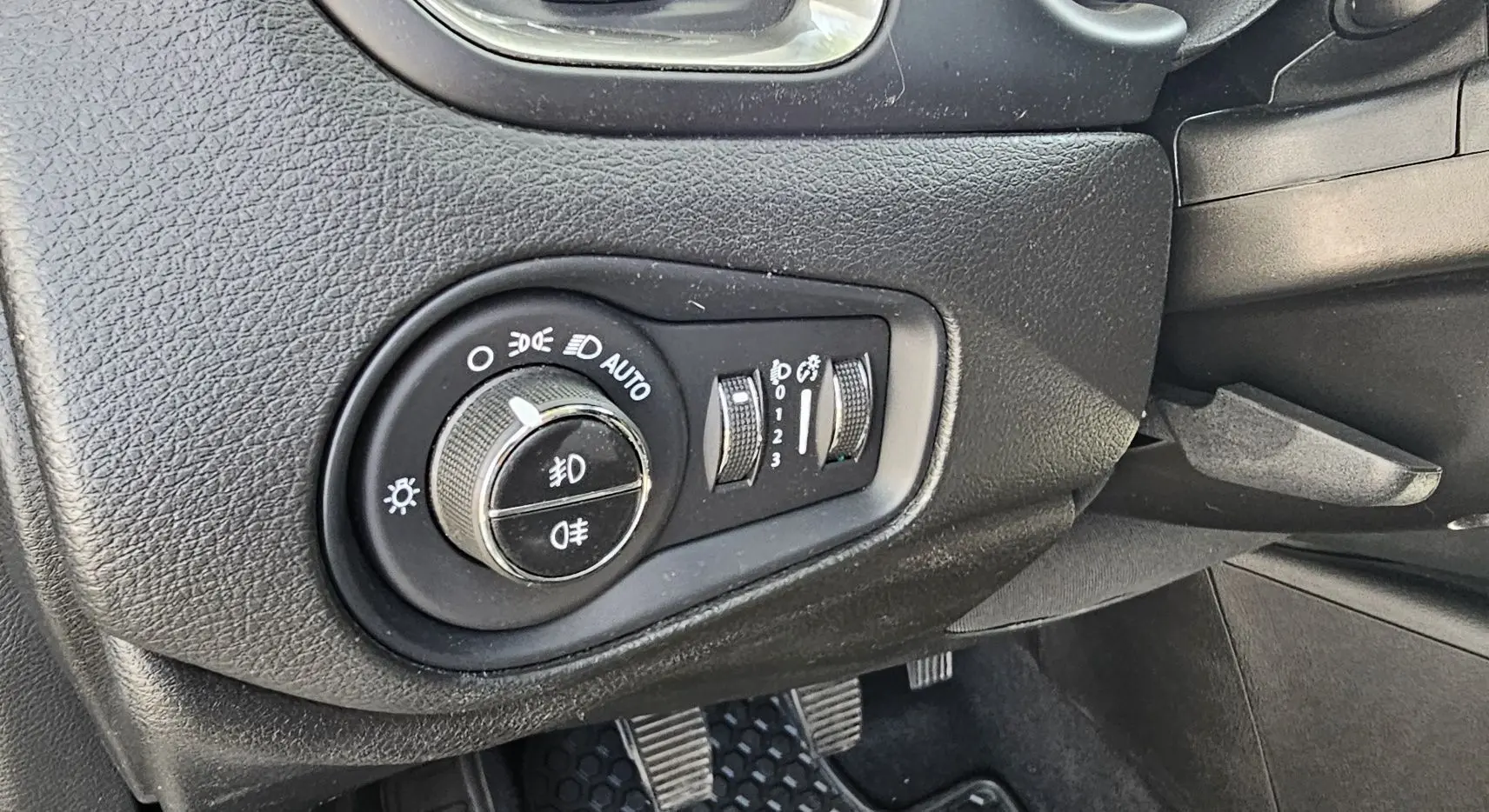Gros plan sur le bouton de commande des phares et réglages d’éclairage du tableau de bord du Jeep Renegade Sting Gray 2020.