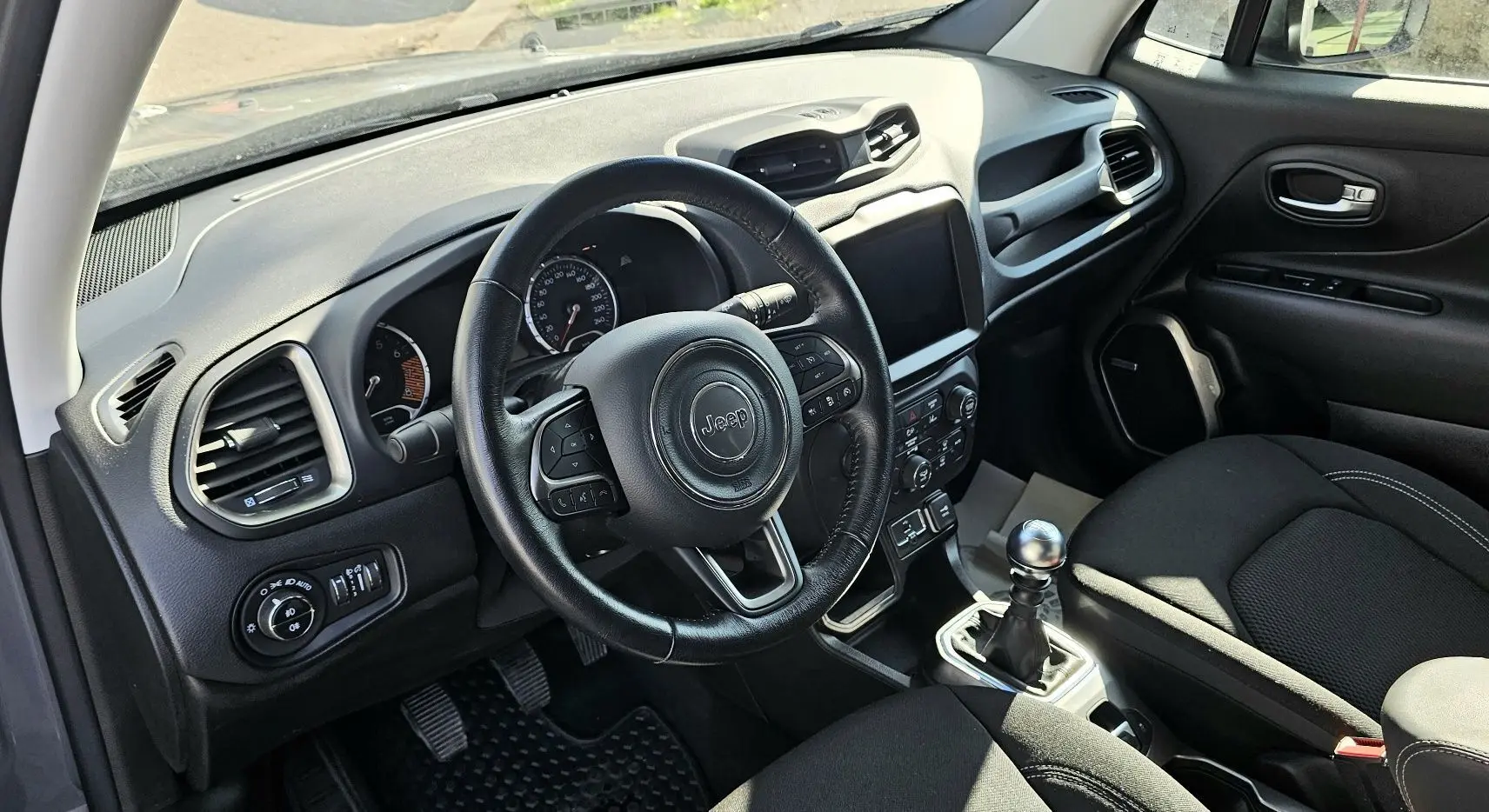 Intérieur du Jeep Renegade 2020 en tissu noir, vue côté conducteur sur le volant, tableau de bord et levier de vitesse manuel.