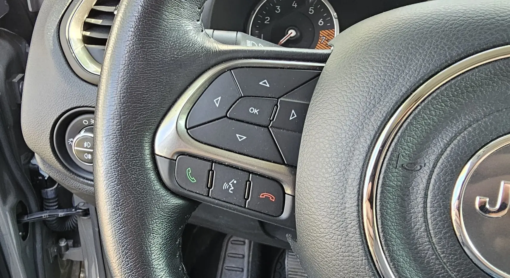 Gros plan sur le volant en cuir noir du Jeep Renegade 2020, avec commandes intégrées et logo central chromé.