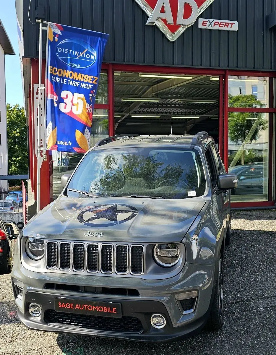 Jeep Renegade Sting Gray vue de face, avec étoile noire sur le capot, stationnée devant un garage AD Expert.