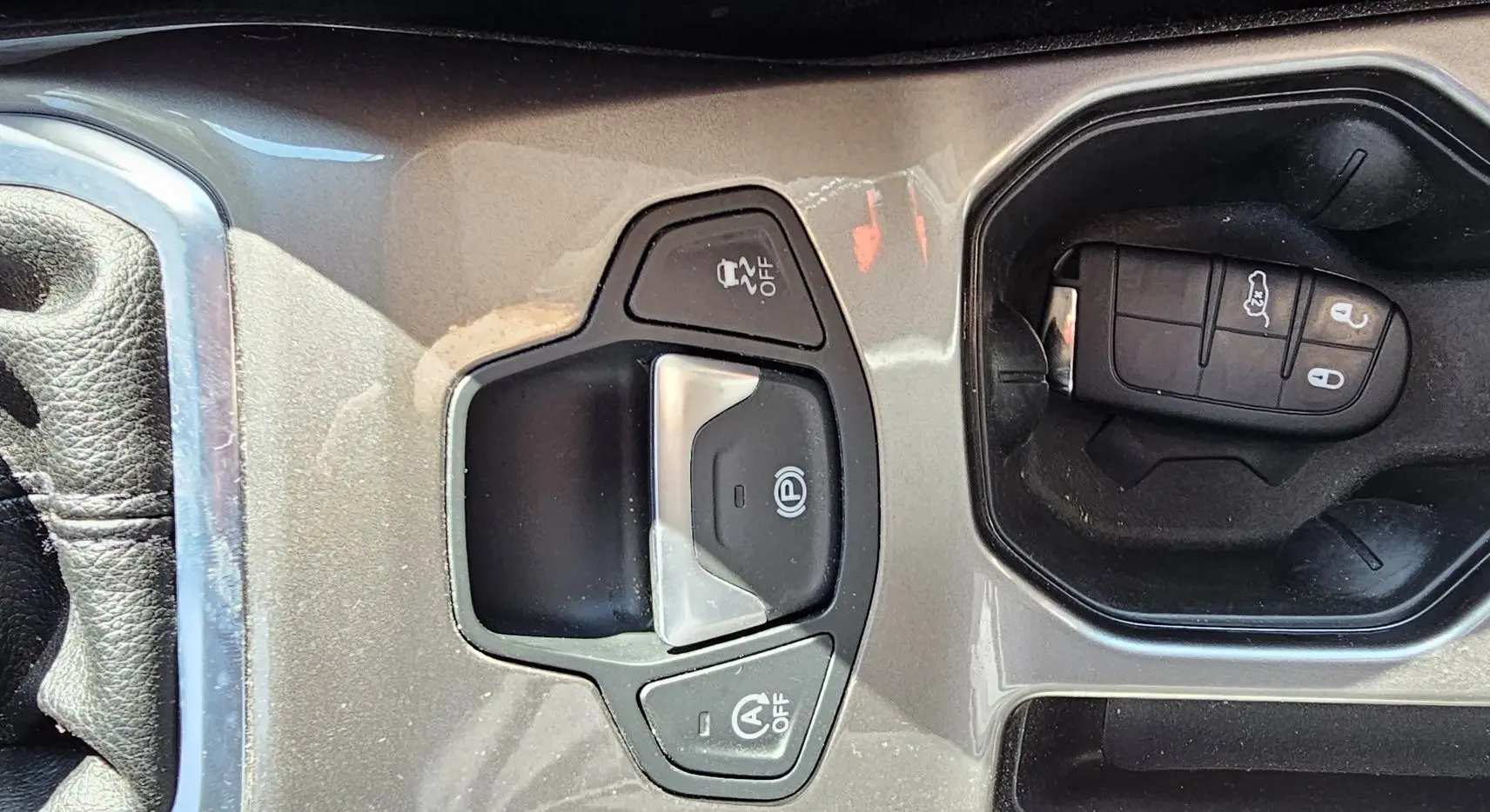 Gros plan sur la console centrale grise du Jeep Renegade 2020 avec clé et commandes électroniques du frein à main et traction.
