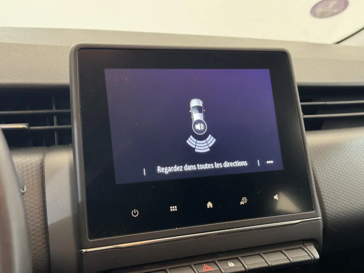Écran tactile central affichant l'alerte de capteurs de stationnement dans l'habitacle d'une Renault Clio blanche.