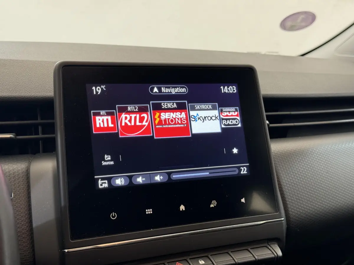 Écran tactile central affichant les radios dans l'habitacle d'une Renault Clio Business blanche, vue de face.