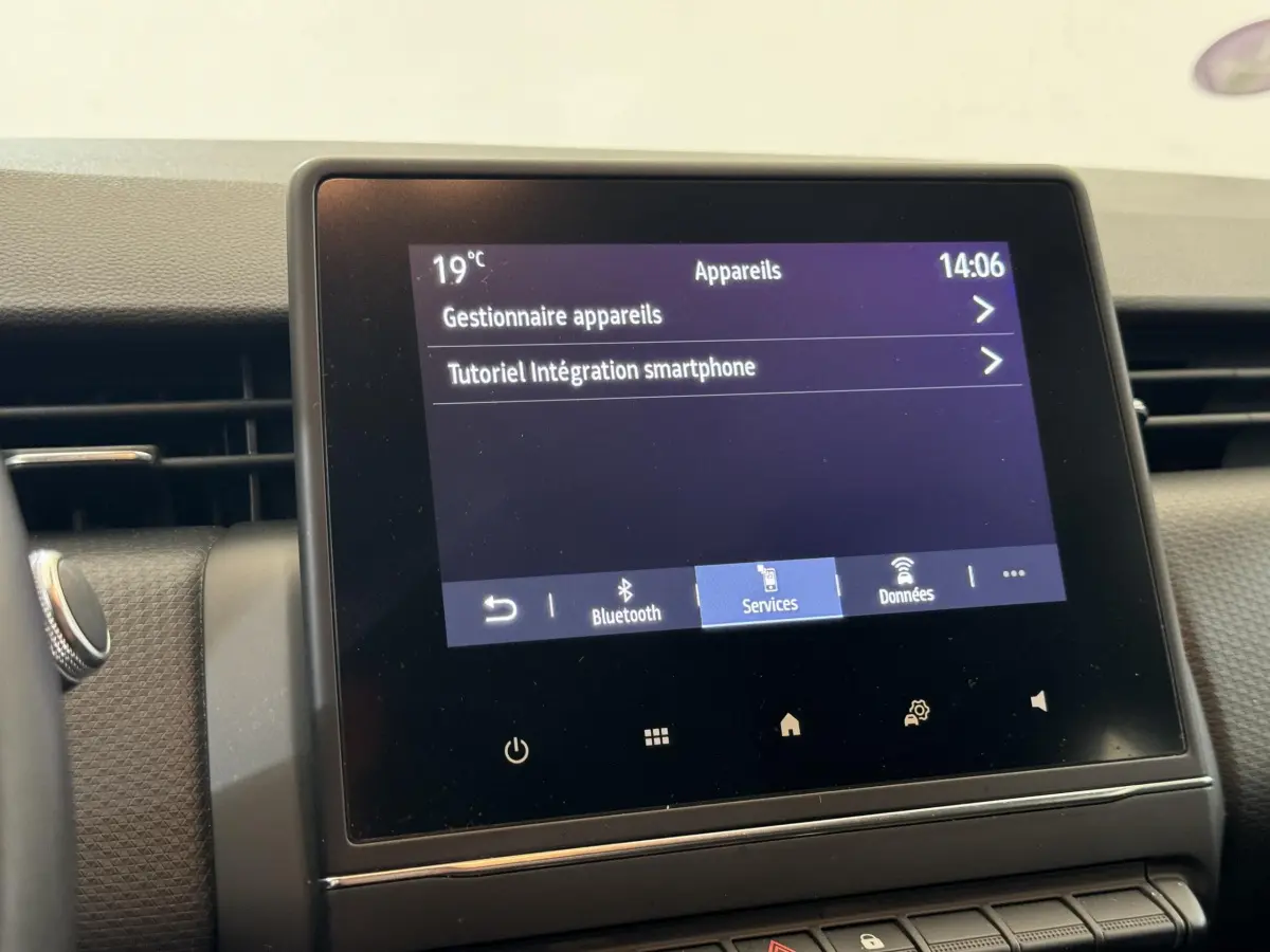 Écran tactile central affichant les options Bluetooth et services dans l'habitacle d'une Renault Clio blanche 2021.