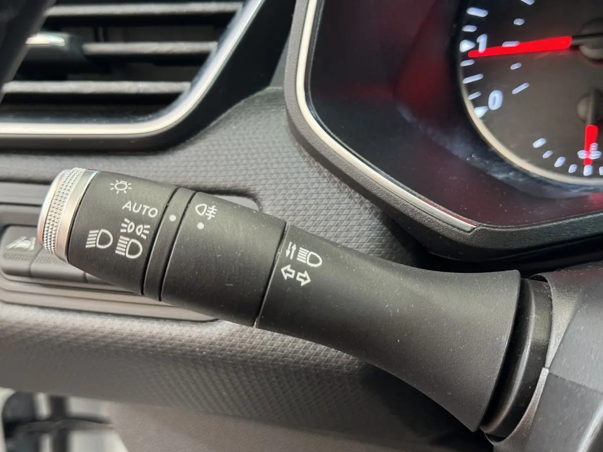 Gros plan sur la commande des phares et clignotants à gauche du tableau de bord de la Renault Clio Business blanche 2021.