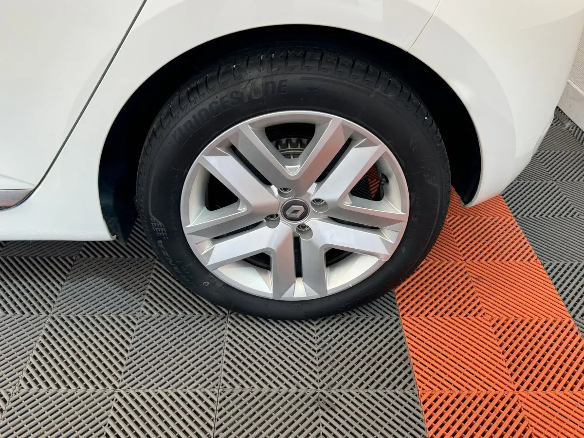Gros plan sur la roue arrière droite blanche d'une Renault Clio Business 2021 avec jante alliage et logo Renault central.