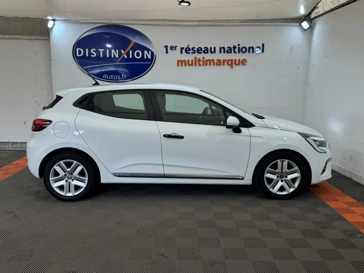 Profil côté gauche d'une Renault Clio blanche Business 2021, avec jantes alliage et feux arrière LED visibles.