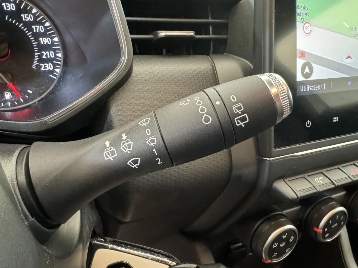Gros plan sur la commande d’essuie-glace noire à gauche du volant dans l’habitacle d’une Renault Clio Business blanche 2021.