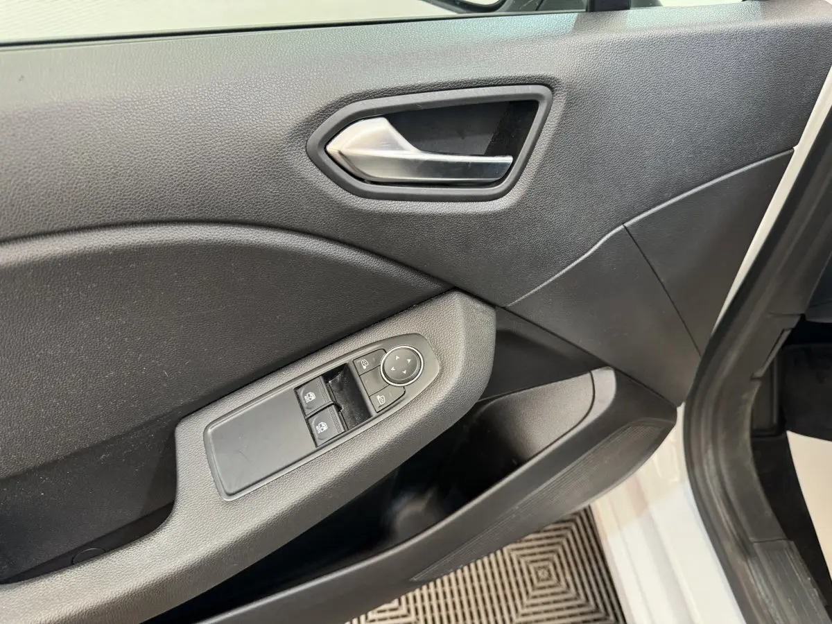 Gros plan sur la porte avant gauche noire d'une Renault Clio blanche, avec commandes des vitres et rétroviseurs.