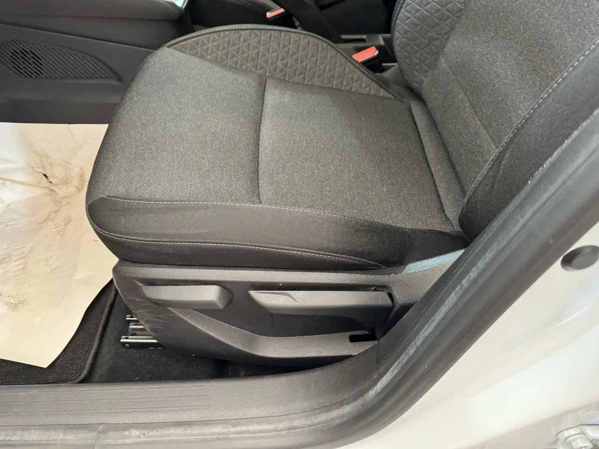 Gros plan sur le siège avant gauche gris foncé de la Renault Clio Business blanche, avec réglages manuels visibles.