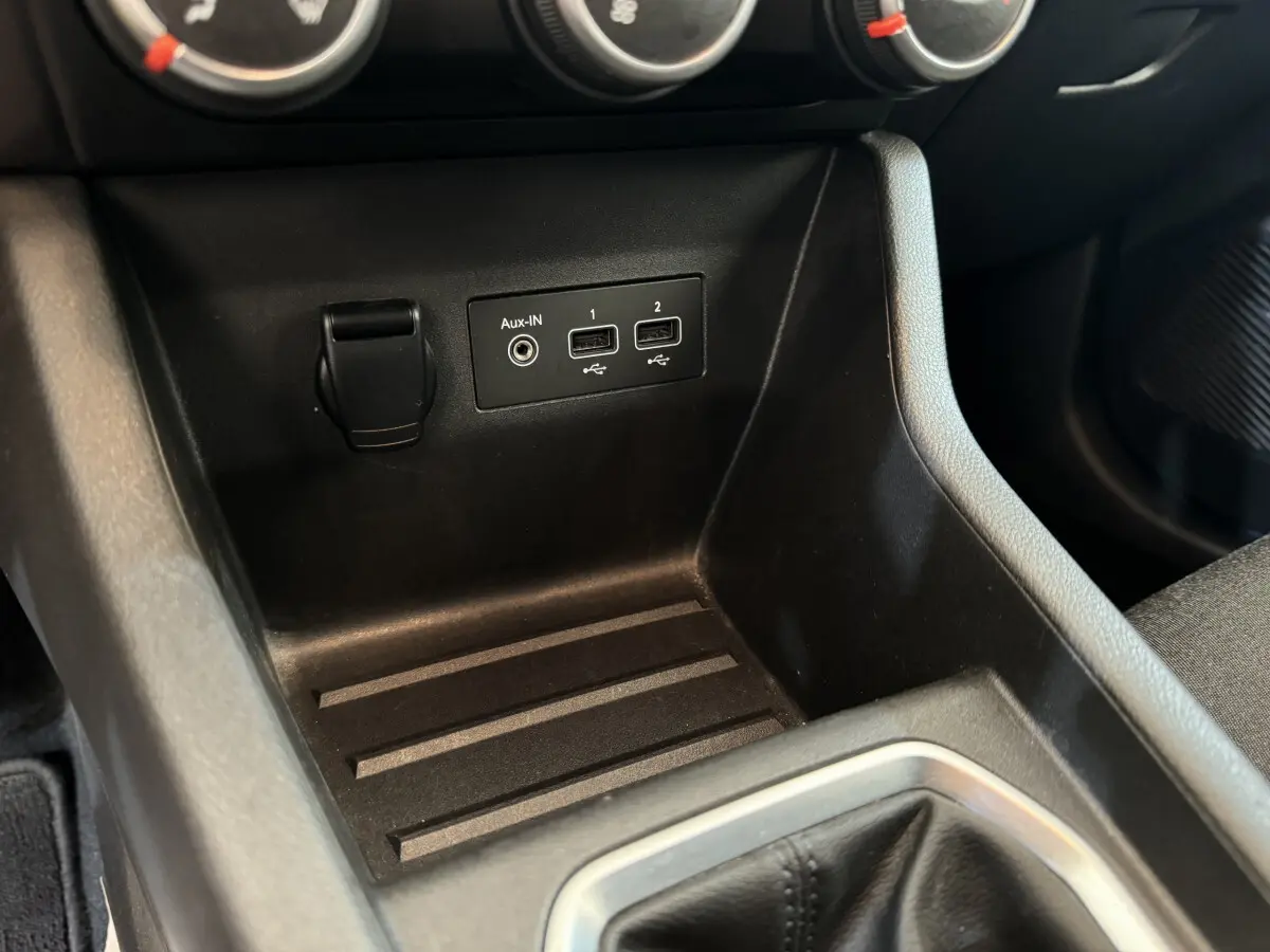 Gros plan sur la console centrale noire de la Renault Clio Business avec ports USB et prise Aux-In visibles.