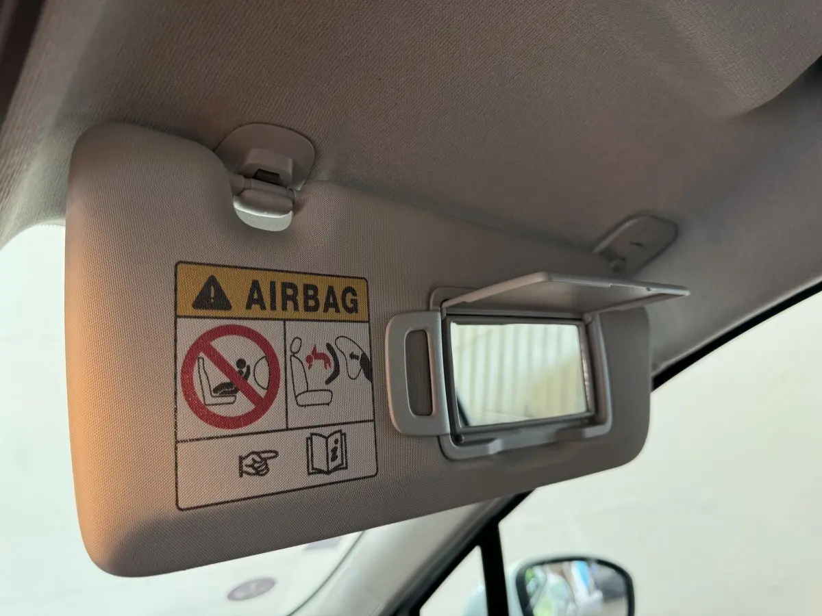 Détail du pare-soleil côté conducteur de la Renault Clio Business blanche 2021 avec miroir de courtoisie ouvert et avertissement airbag.