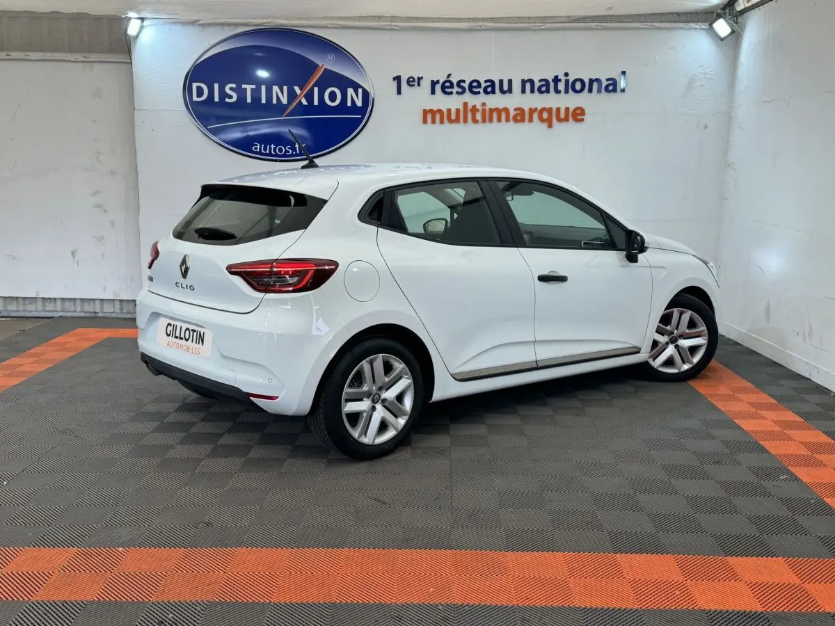 Renault Clio Business blanche vue de trois quarts arrière droit, dans un showroom avec logo Distinxion en arrière-plan.