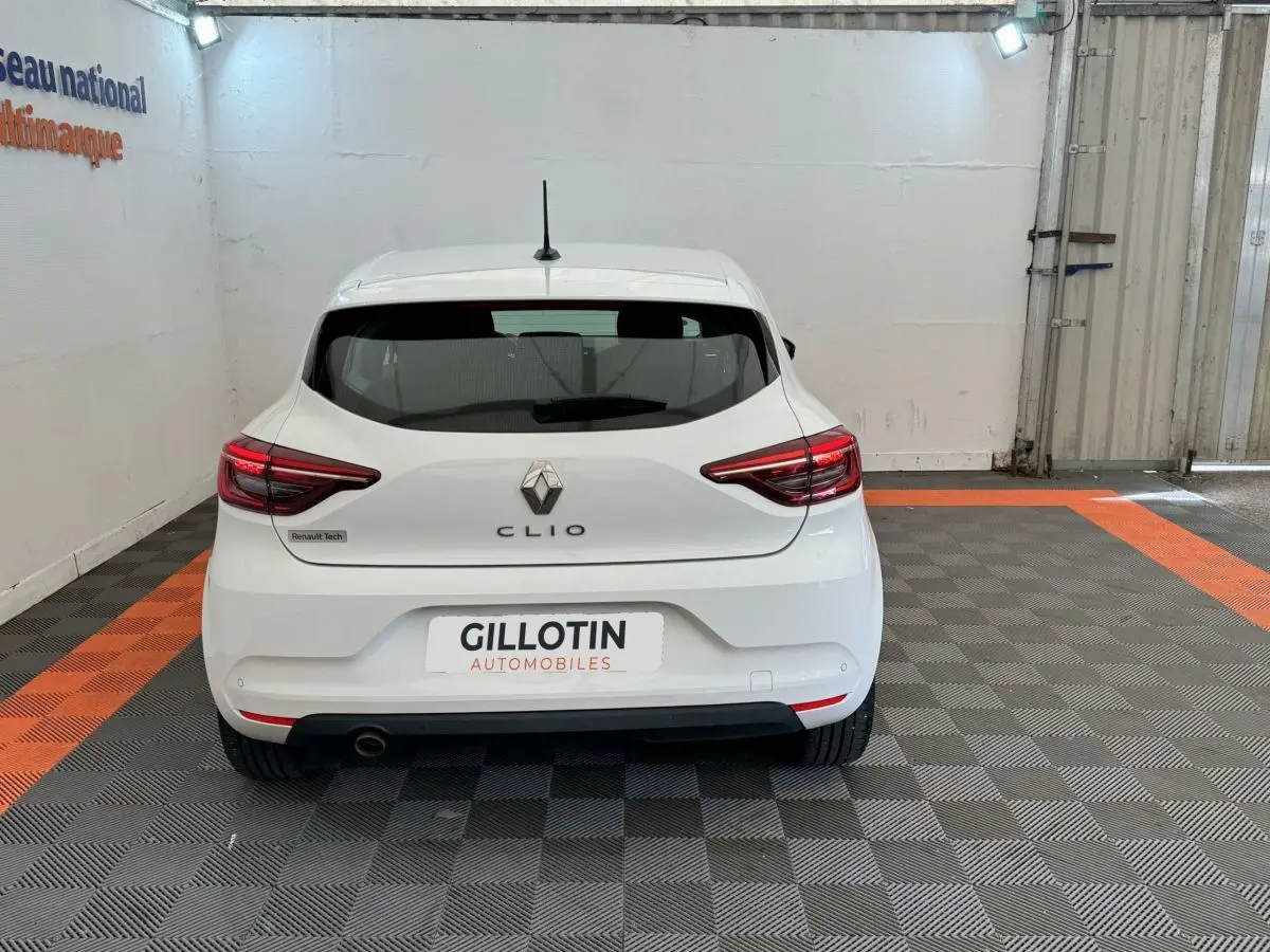 Vue arrière d'une Renault Clio blanche 2021 avec feux LED et logo Renault visible sur un sol à damiers gris et orange.
