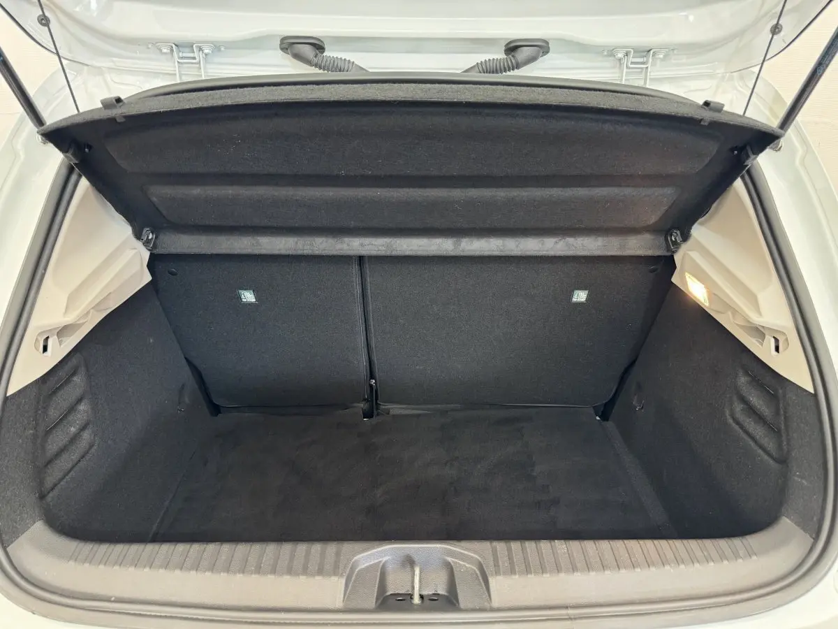 Coffre ouvert de la Renault Clio Business blanche, vue de l'arrière montrant l'espace de chargement vide et propre.