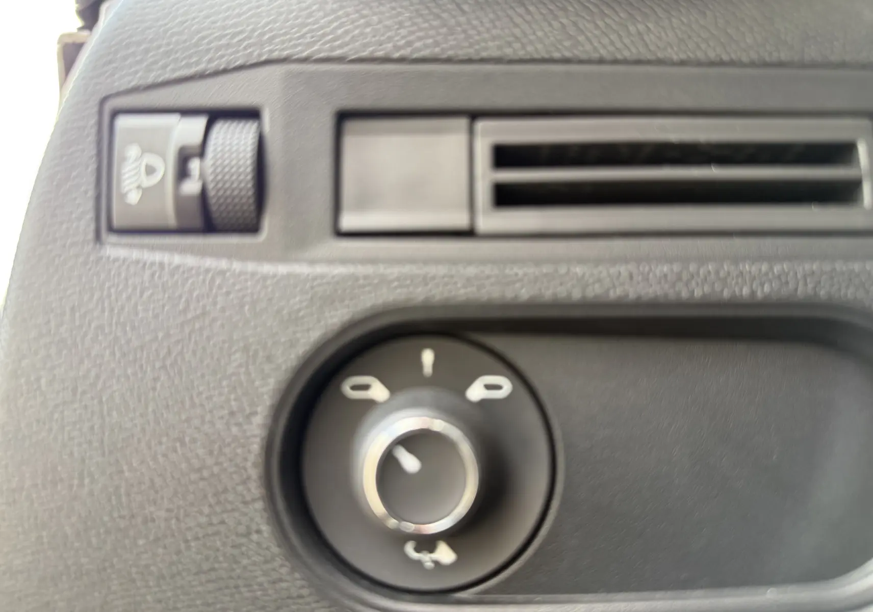 Gros plan sur la commande des rétroviseurs et la molette de réglage d’éclairage dans l’habitacle d’une DS3 hybride gris Artense.