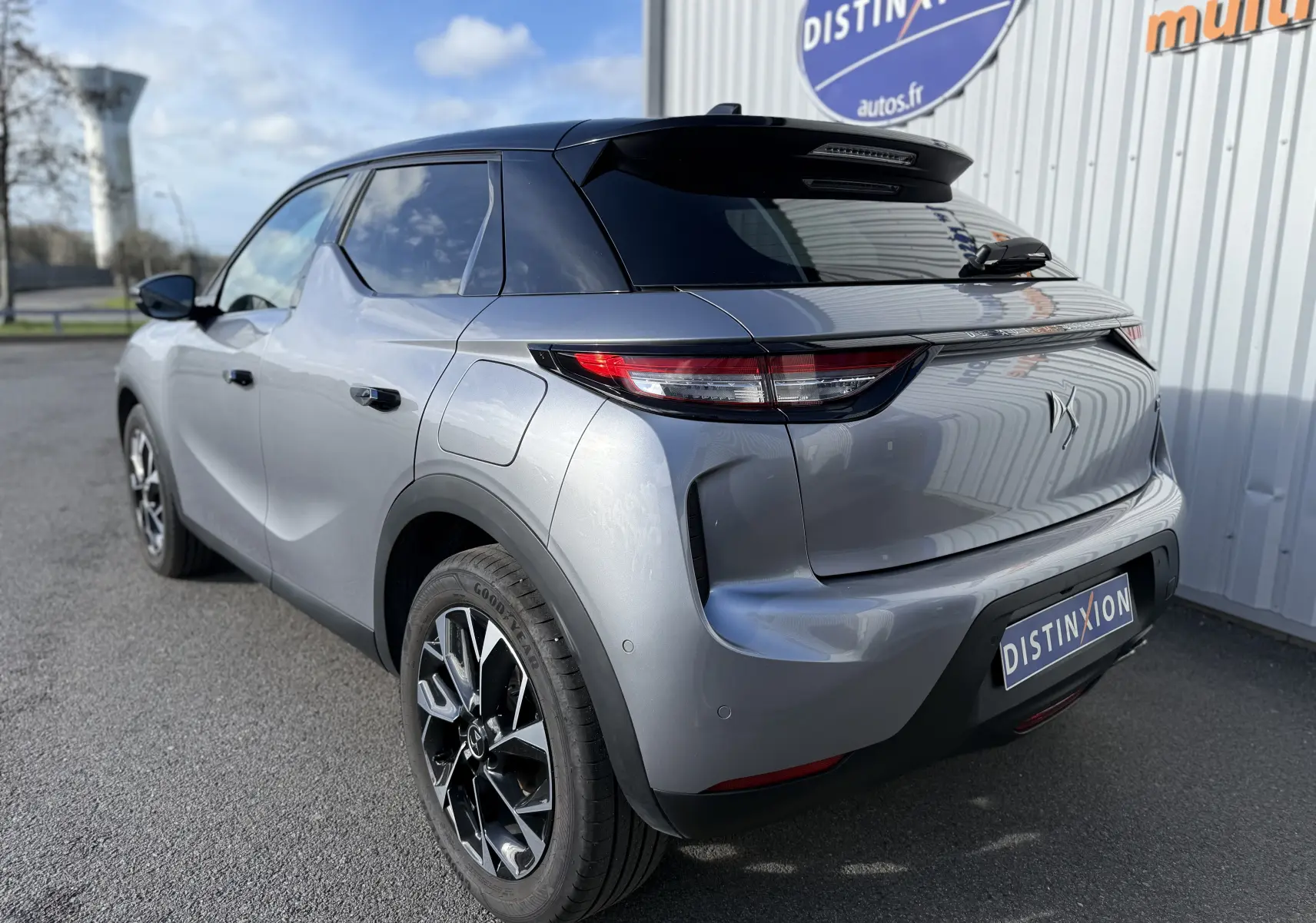 Vue 3/4 arrière droite d'une DS3 hybride 2025 gris Artense avec toit noir et jantes biton distinctives.