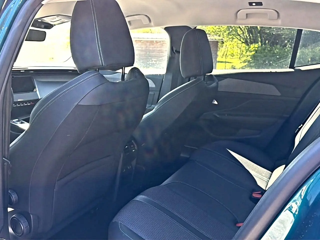 Vue intérieure arrière droite de la Peugeot 408 Hybrid 145 allure bleu, montrant la banquette et les sièges avant noirs.