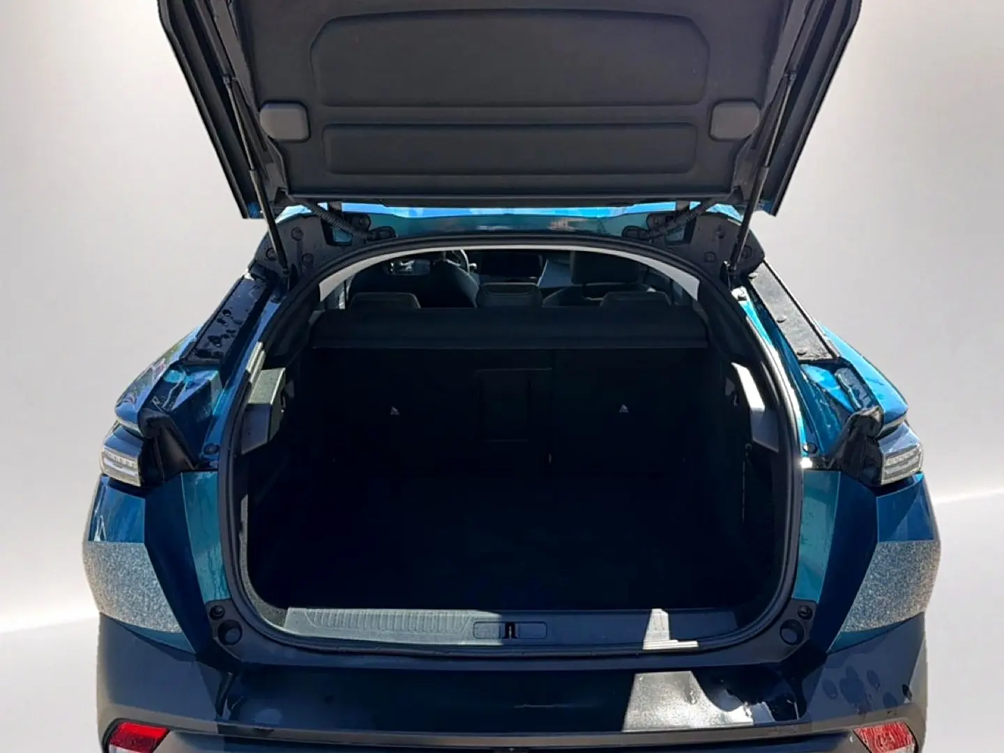 Vue arrière ouverte du coffre d'une Peugeot 408 Hybrid 145 allure e-dcs6 bleu 2025, montrant l'espace de chargement vide.