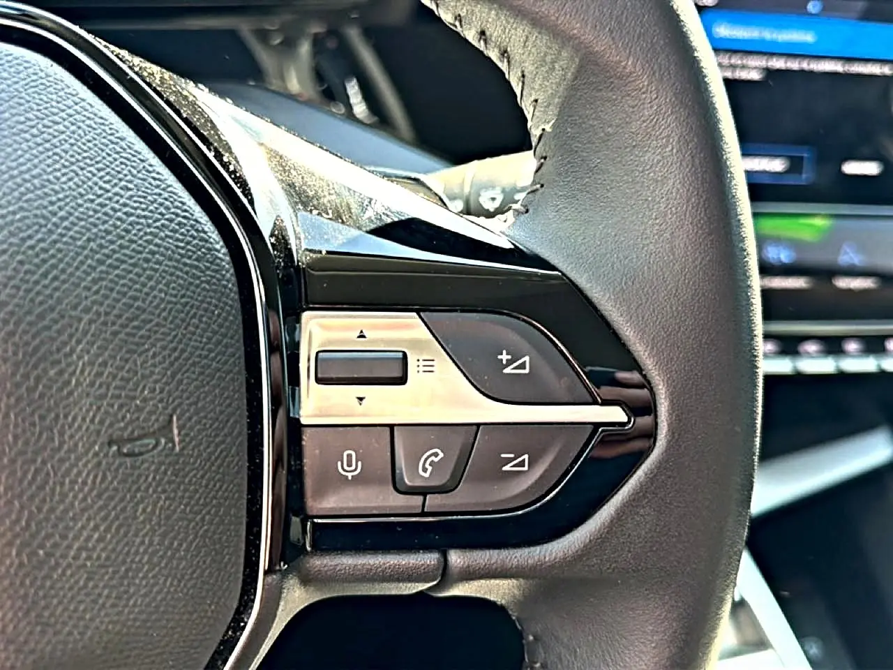 Gros plan sur les commandes vocales et téléphone au volant cuir noir du Peugeot 408 Hybrid 145 allure 2025.