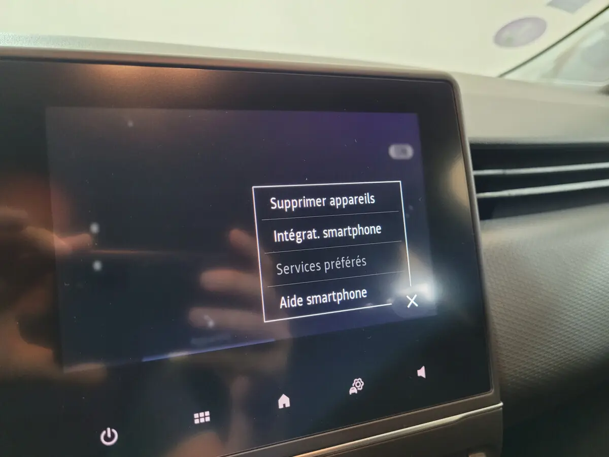 Écran tactile central affichant les options smartphone dans l'habitacle d'une Renault Clio Business blanche de 2021.