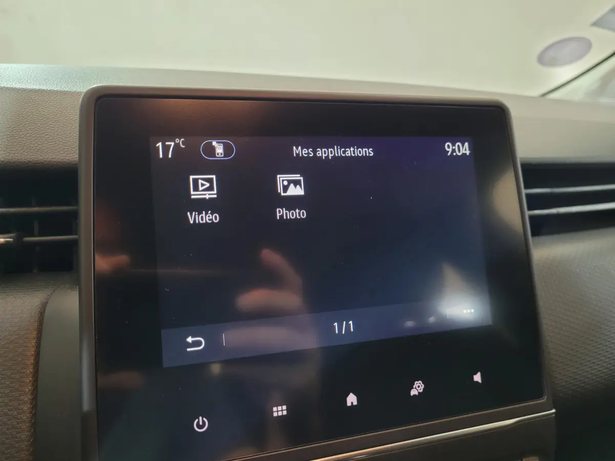 Écran tactile central affichant les applications vidéo et photo dans l'habitacle d'une Renault Clio Business blanche.