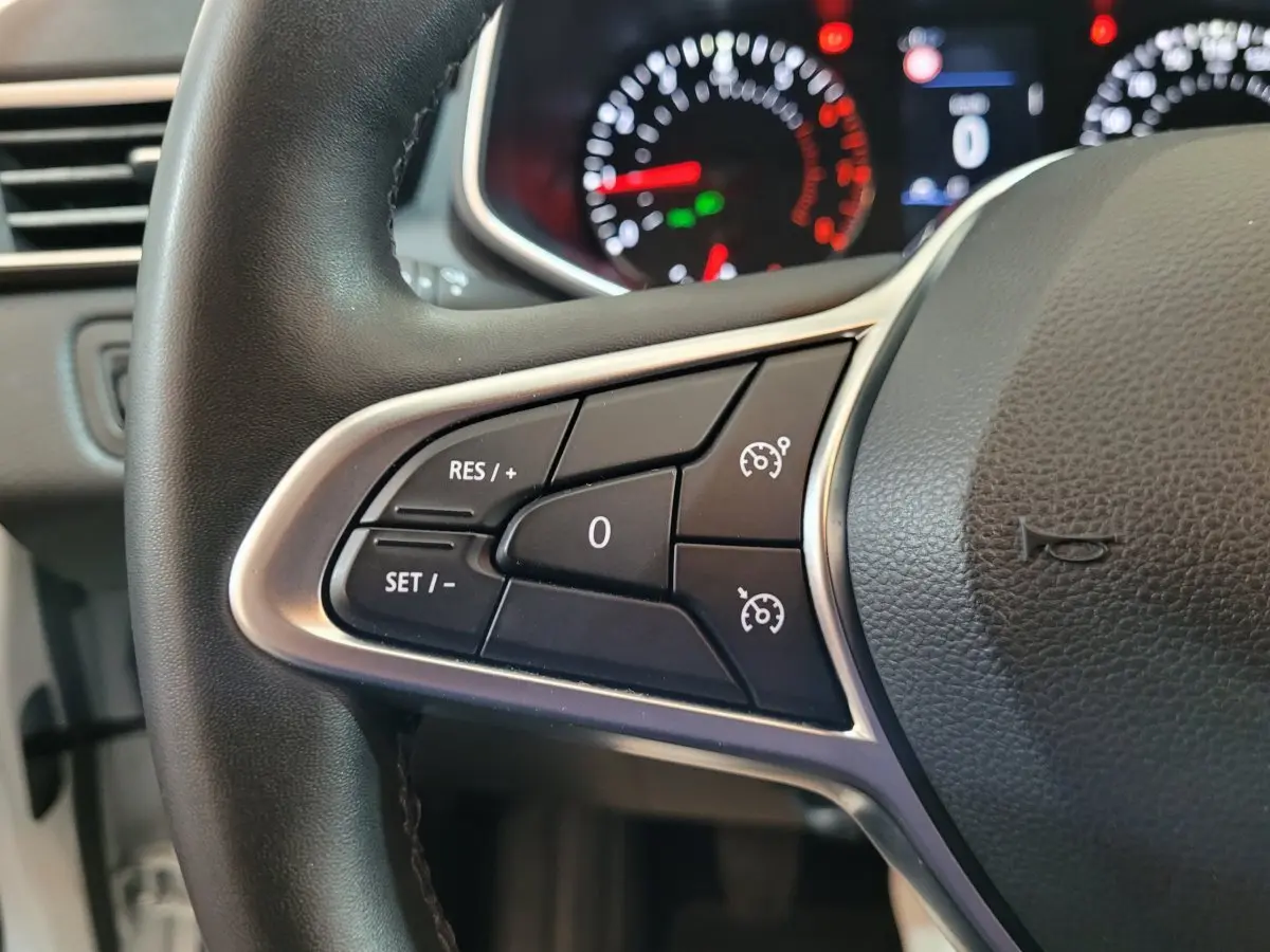 Gros plan sur le volant cuir synthétique de la Renault Clio Business blanc, avec commandes de régulateur de vitesse visibles.