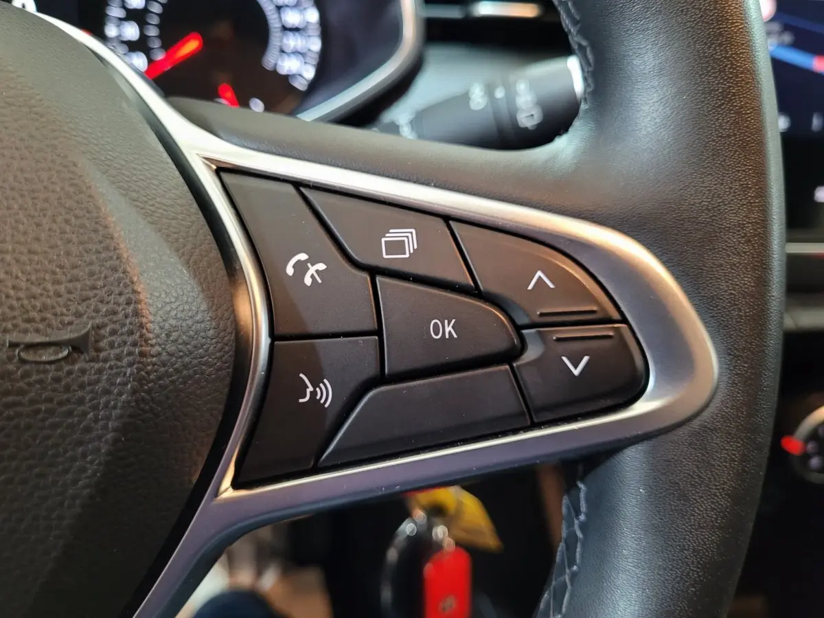 Gros plan sur les commandes multifonctions du volant cuir noir de la Renault Clio Business blanche de 2021.