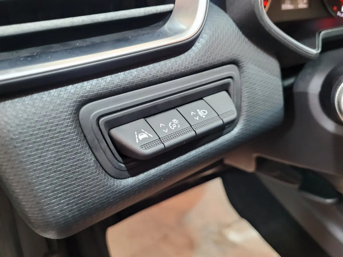 Gros plan sur les commandes d'assistance à la conduite sur tableau de bord noir de la Renault Clio Business blanche.