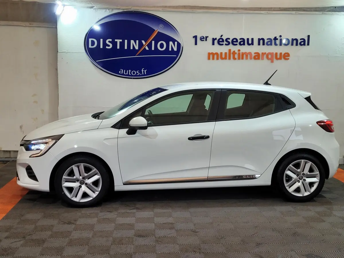 Profil côté gauche d'une Renault Clio Business blanche de 2021, avec jantes alliage et feux LED visibles.