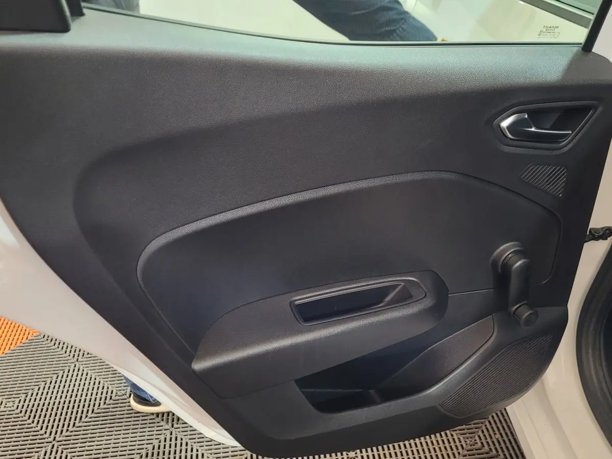 Vue intérieure côté gauche de la porte arrière noire d'une Renault Clio Business blanche avec manivelle de vitre.